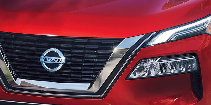 Close-up of a red Nissan car front grille and headlight