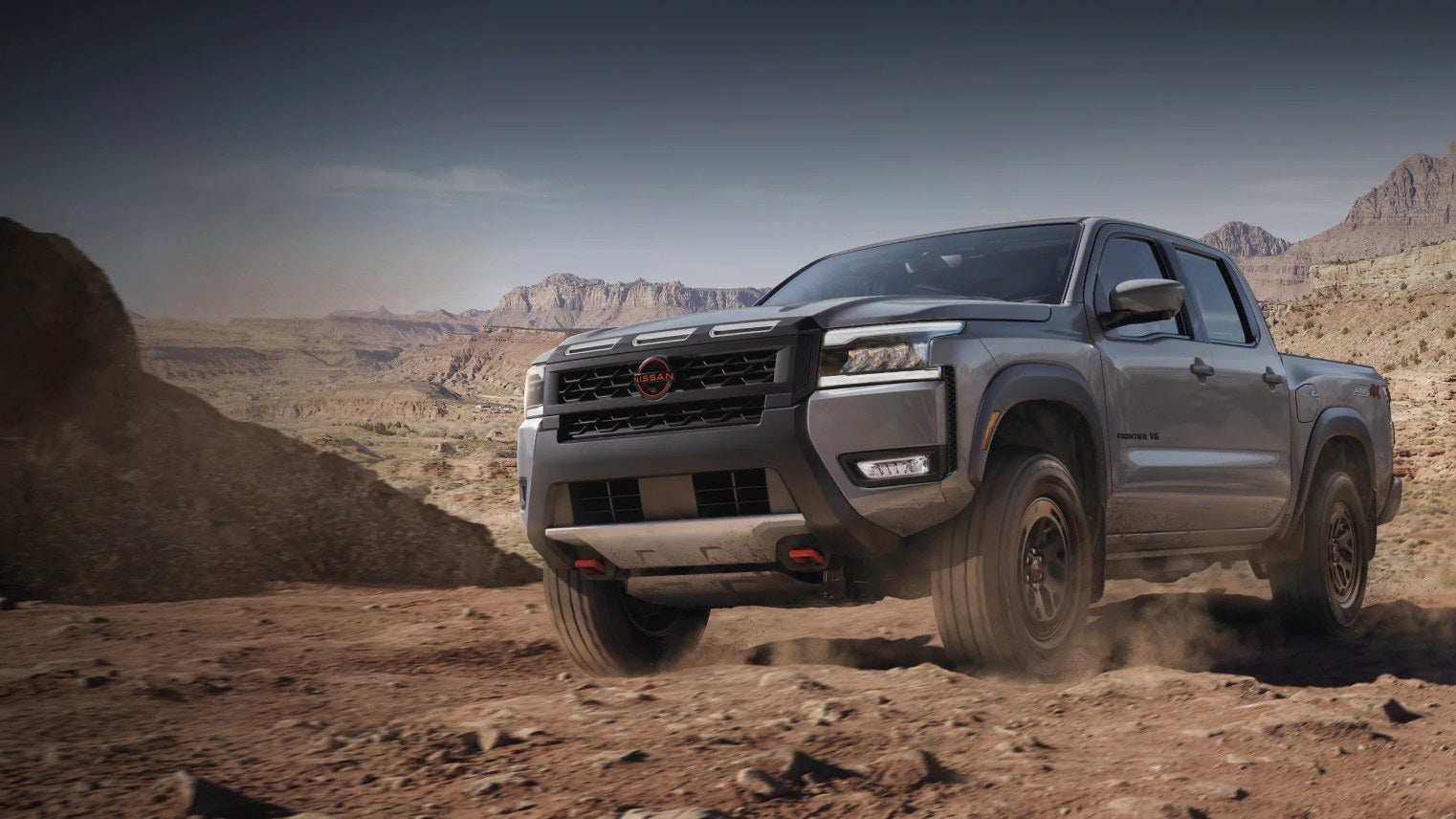 Nissan Frontier pickup truck driving across a rocky desert landscape