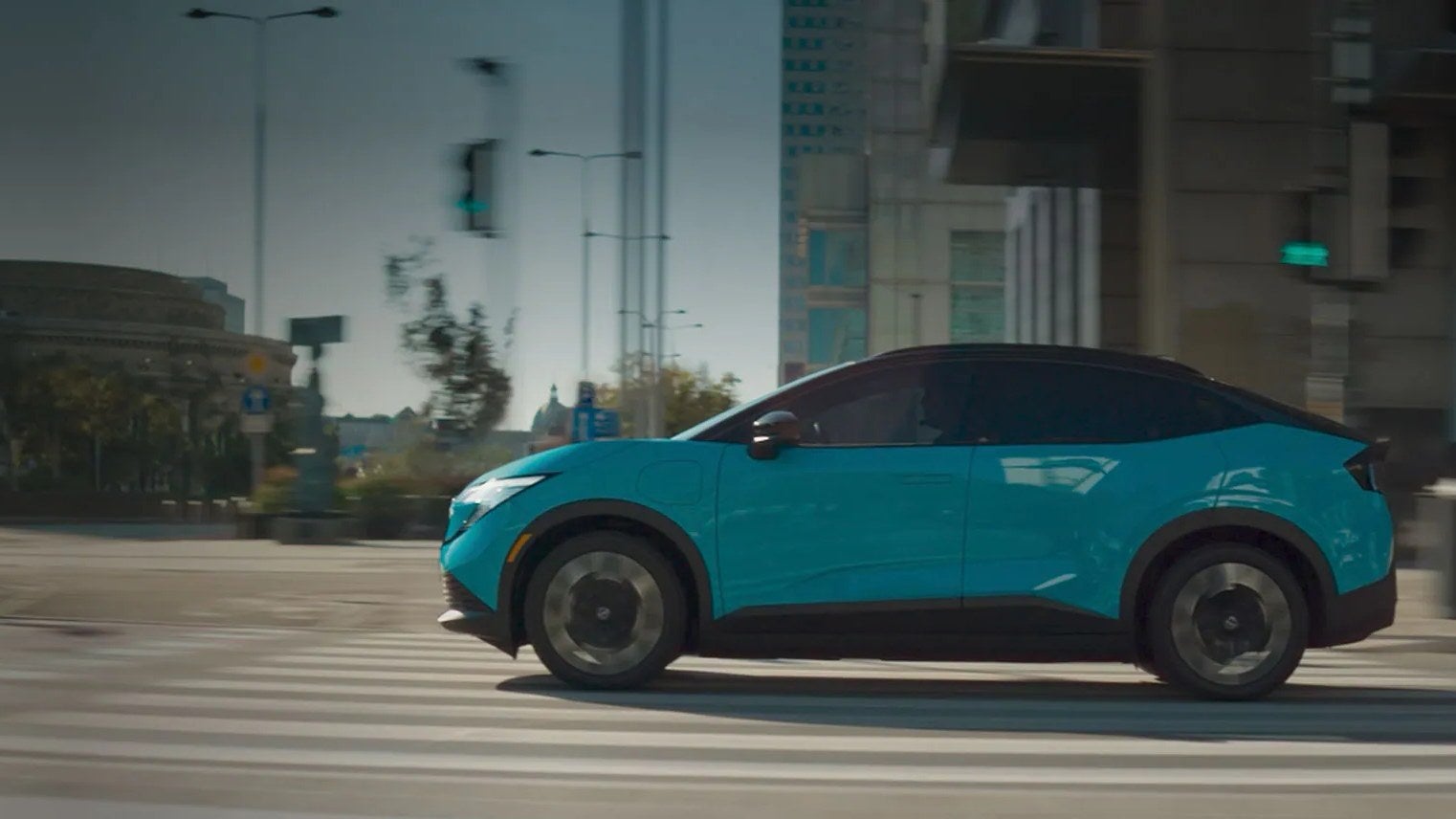 Blue 2026 Nissan LEAF electric crossover driving through a city intersection